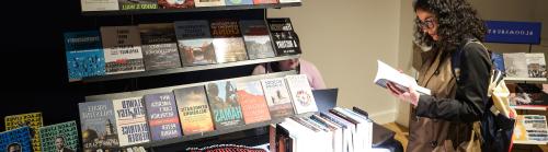 A conference delegate reading a book by an exhibition stand